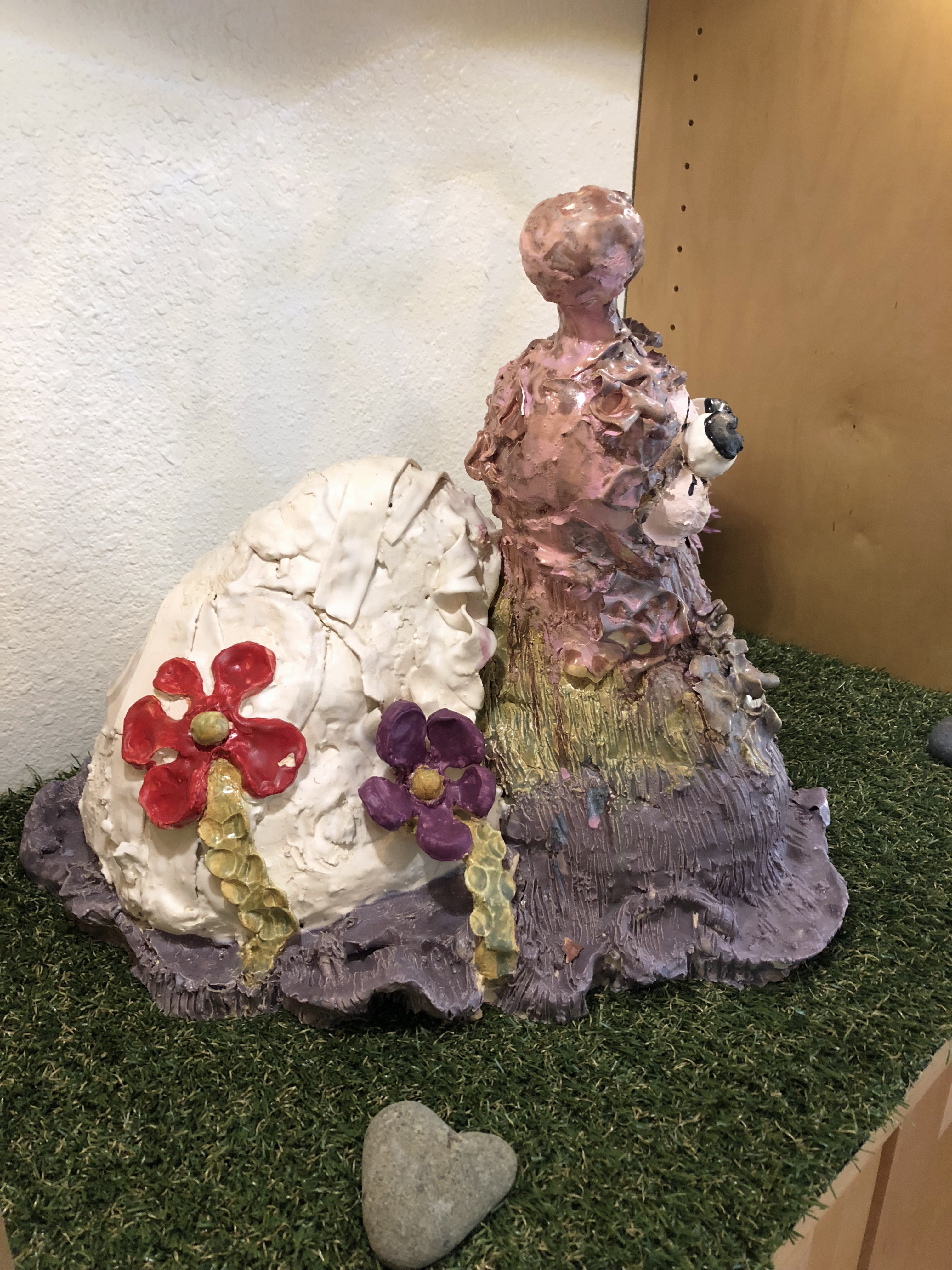 Side view close up of a lavender ceramic snail scupture with carooty eyes